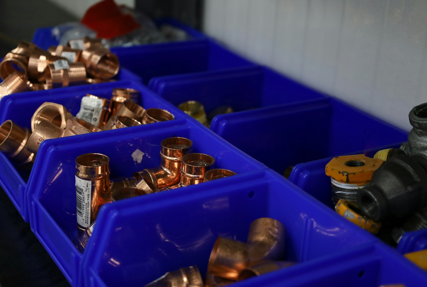 Various copper and iron plumbing fittings organized in blue bins.